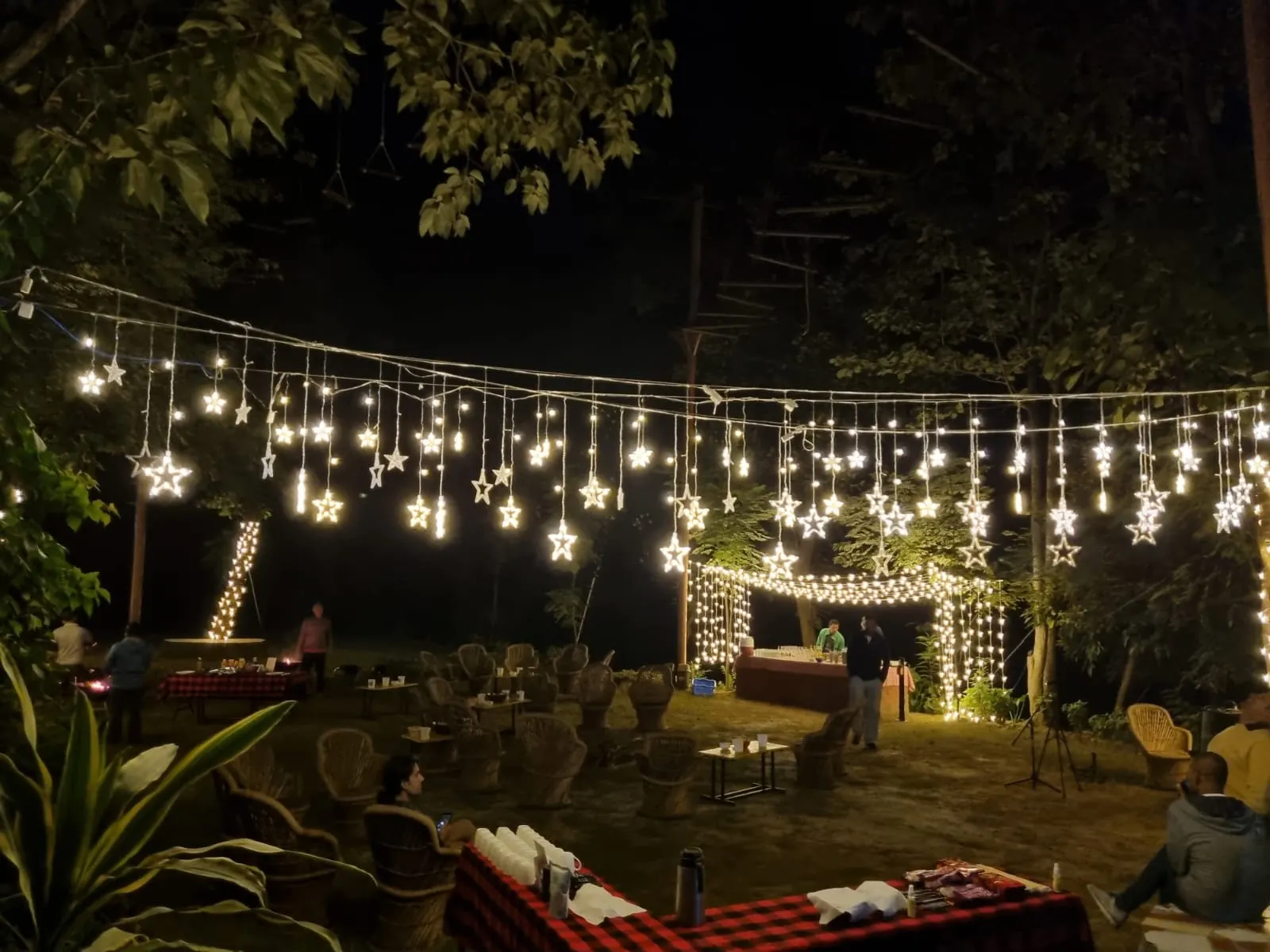 String-light-lit outdoor event setup with cane chairs at Atali Ganga